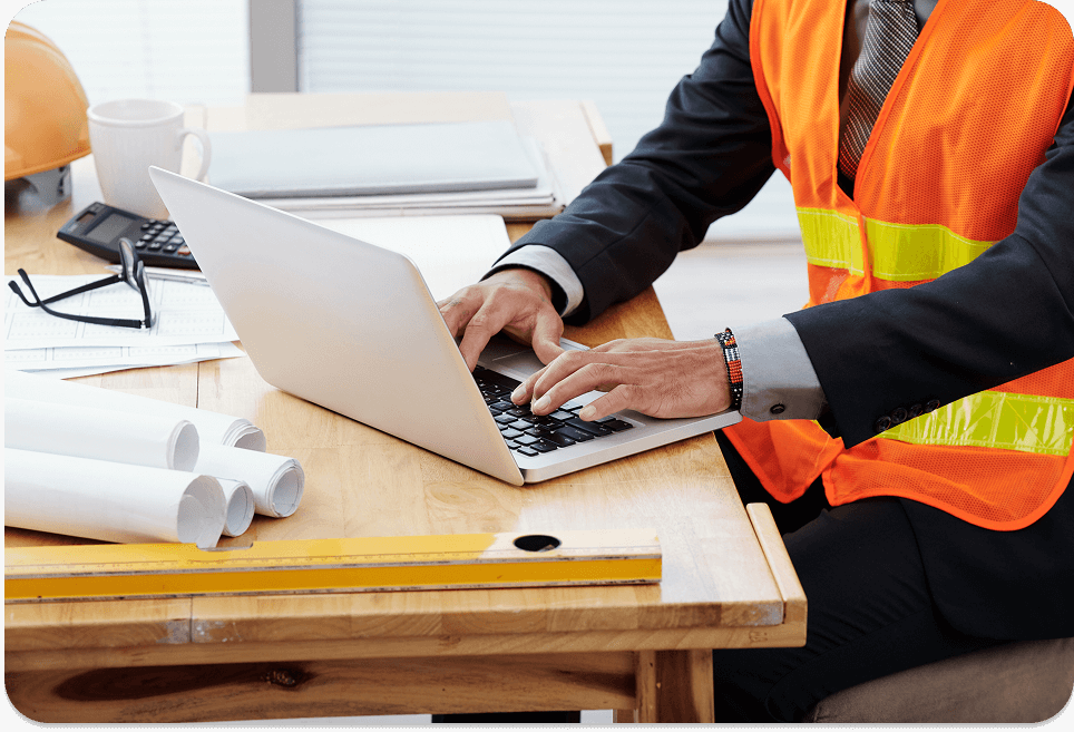 unrecognizable man neon safety vest business suit sitting desk using laptop 1 1